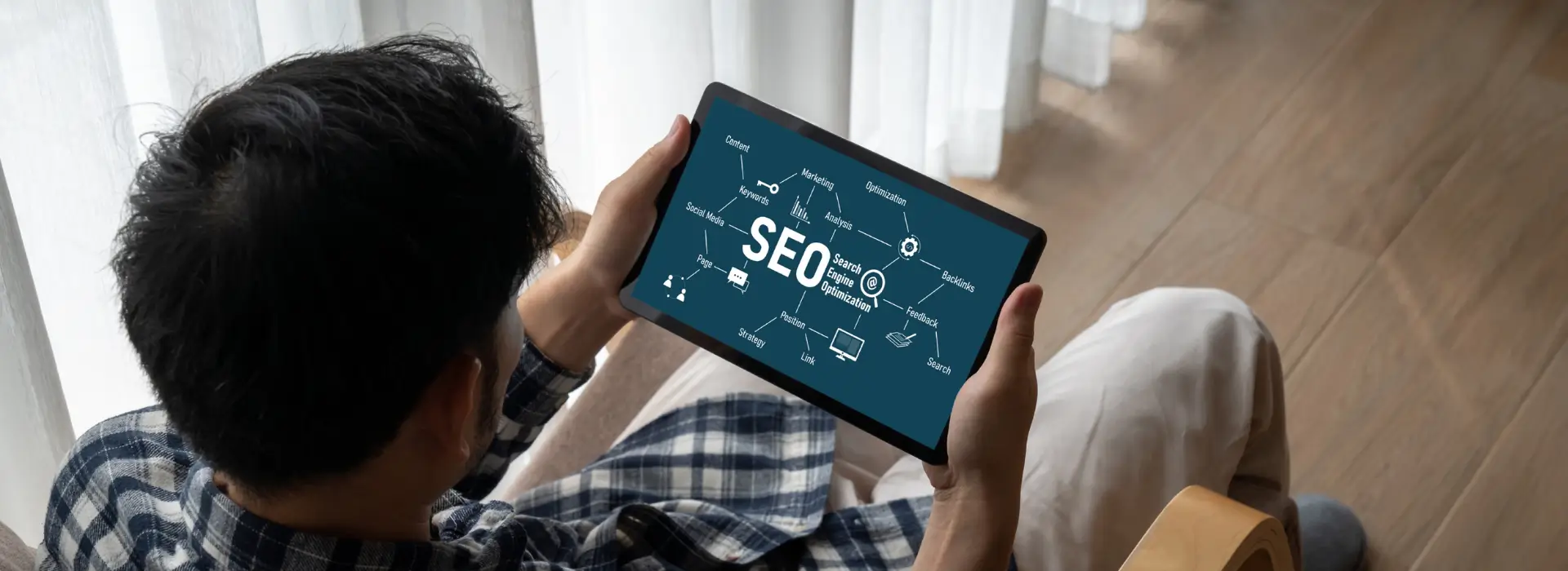Référencement de site internet - Homme consultant une tablette affichant le mot SEO, illustrant l’optimisation du référencement de site internet pour améliorer la visibilité en ligne.